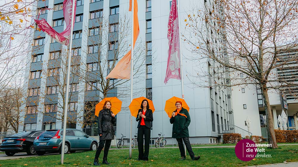 Samira Terpoorten, Prof. Borna Relja und Sandra Tiefel haben die orange Fahne vor dem Campustower gehisst (Foto: Jana Dünnhaupt / Uni Magdeburg)