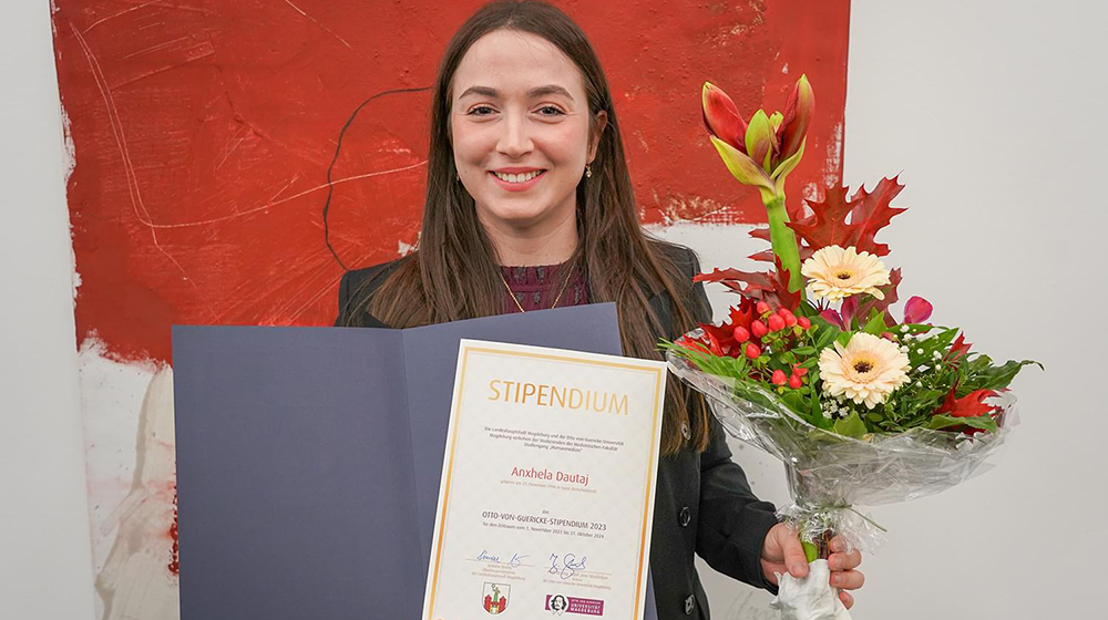 Portrait of medical student Anxhela Dautaj with certificate and bouquet of flowers in hand at the presentation of the scholarship (Photo: Laura Thümler / City of Magdeburg)