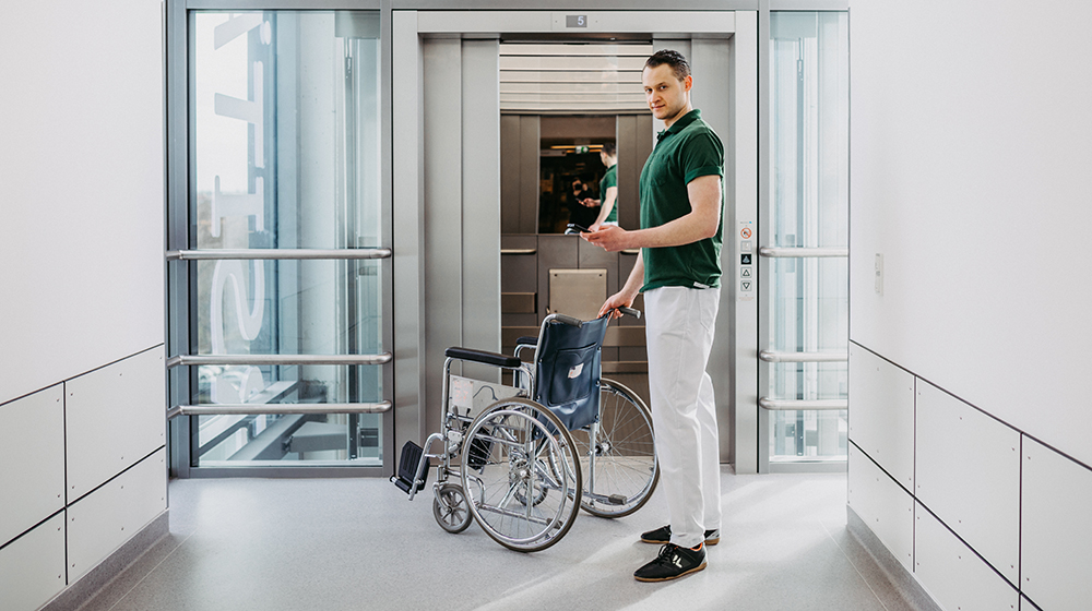 Auf dem Handy hat Oleg Lobach vom Medizinischen Begleitdienst alle Informationen zu den Patienten, die er von Station zu Station bringt.