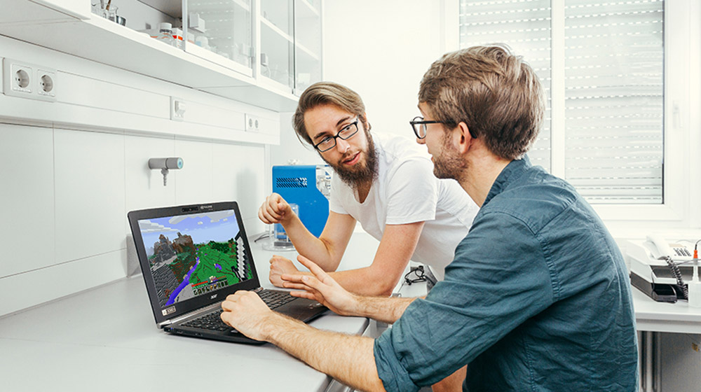 Die Psychologiestudenten Thomas Birnbaum (li.) und Valentin Baumann (re.) besprechen eine virtuelle Umgebung, die Kinder und Jugendliche erkunden sollen. Beide haben gerade ihre Masterarbeit abgeschlossen zum Thema „Behavioral Tagging“, dem besseren Speichern von Lehrinhalten durch zeitlich nahe Präsentation von neuen Eindrücken