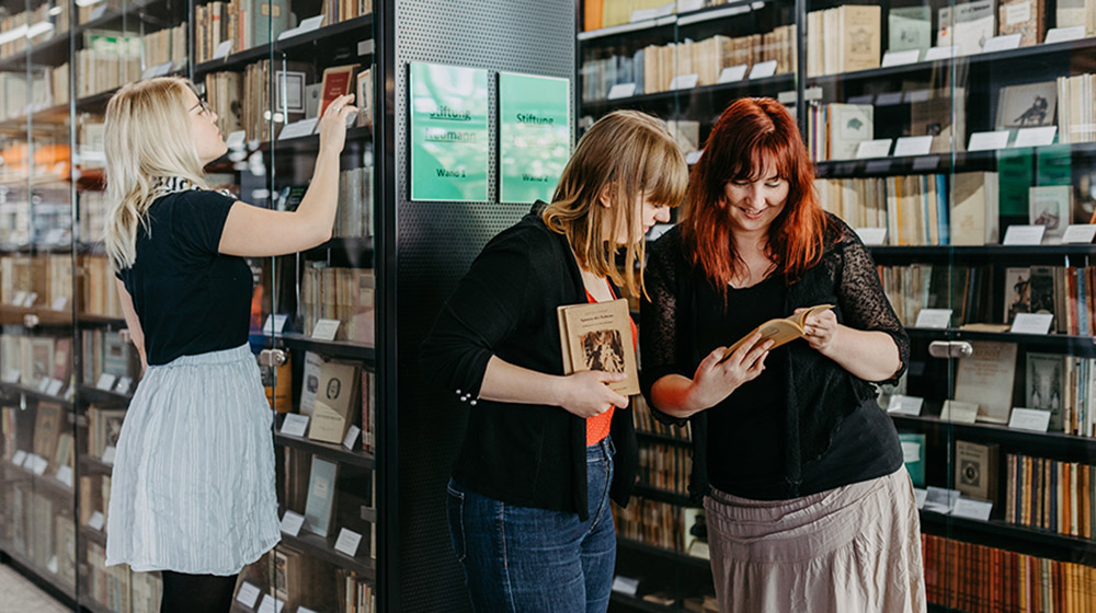 Die Studentinnen Sharline Dünow, Paula Engel und Diana Richter (v.li.) arbeiten in der Bibliothek der Uni Magdeburg mit Büchern, die im Zweiten Weltkrieg als Feldpost verschickt worden waren.