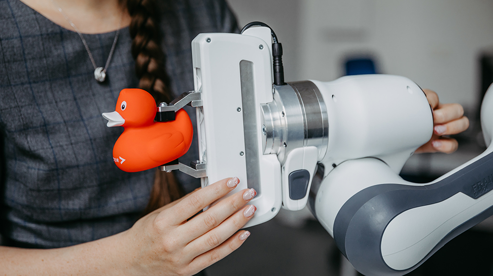 Der Roboterarm hält eine Gummiente 