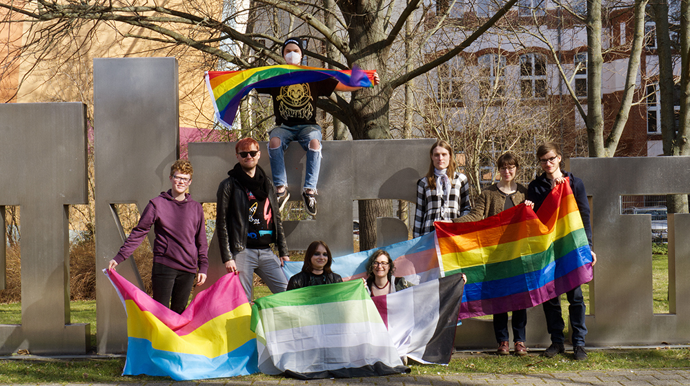 Das Team der studentischen Initiative OVGUpride vor der uniporta mit Regenbogenfahnen (c) privat
