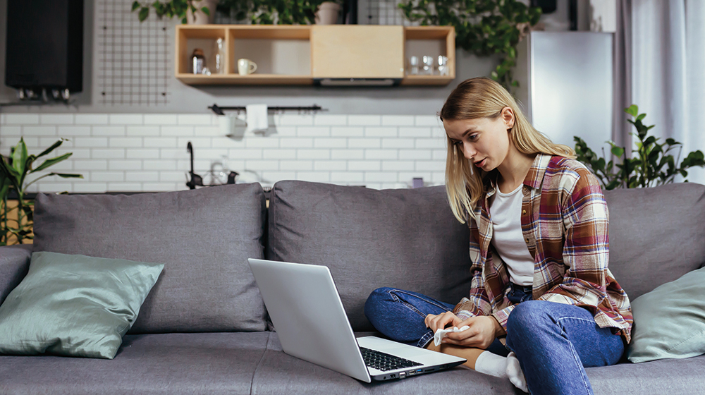 Frau sitzt mit Laptop auf der Couch und chattet per Video (c) shutterstock voronaman