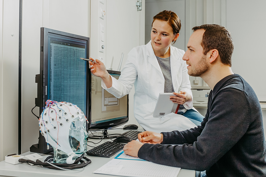 Im Kontrollraum überwachen die technische Assistentin und der Versuchsleiter die EEG-Messung aus 64 Kanälen, über die Span- nungsschwankungen auf der Kopfoberfläche abgeleitet werden. (c) CBBS, OVGU Magdeburg, D. Mahler