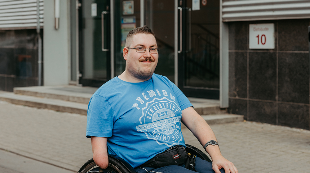 Portrait of Matthias Scheer in a wheelchair in front of building 10 (Photo: Jana Dünnhaupt / Uni Magdeburg)