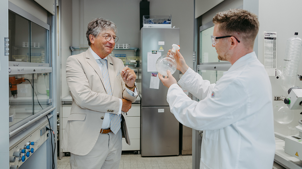 Prof. Schinzer schaut sich die Arbeit eines Nachwuchswissenschaftlers im Labor an (c) Jana Dünnhaupt / Uni Magdeburg