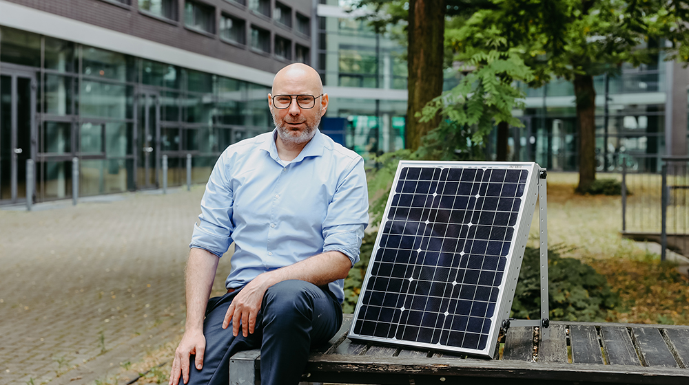 Prof. Sven Müller sitzt neben einem Photovoltaik-Panel (c) Jana Dünnhaupt Uni Magdeburg