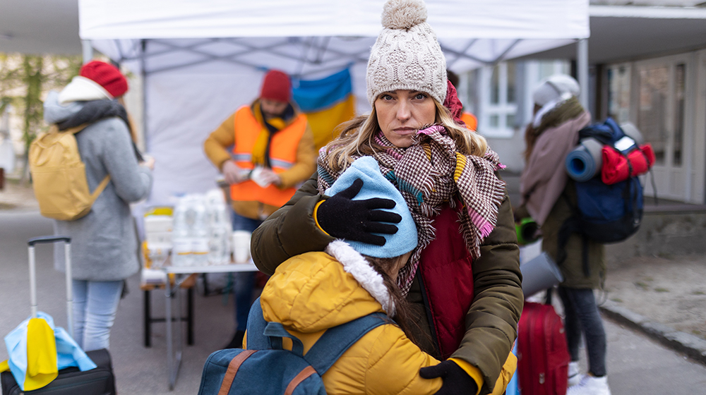 Ukrainische Frau auf der Flucht hält ihr Kind am Grenzübergang in den Armen (c) Shutterstock Halfpoint