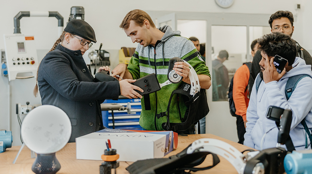 Henri Paetz zeigt Interessierten in der StudierendenWerkstatt die Exoskelettarme (c) Hannah Theile Uni Magdeburg