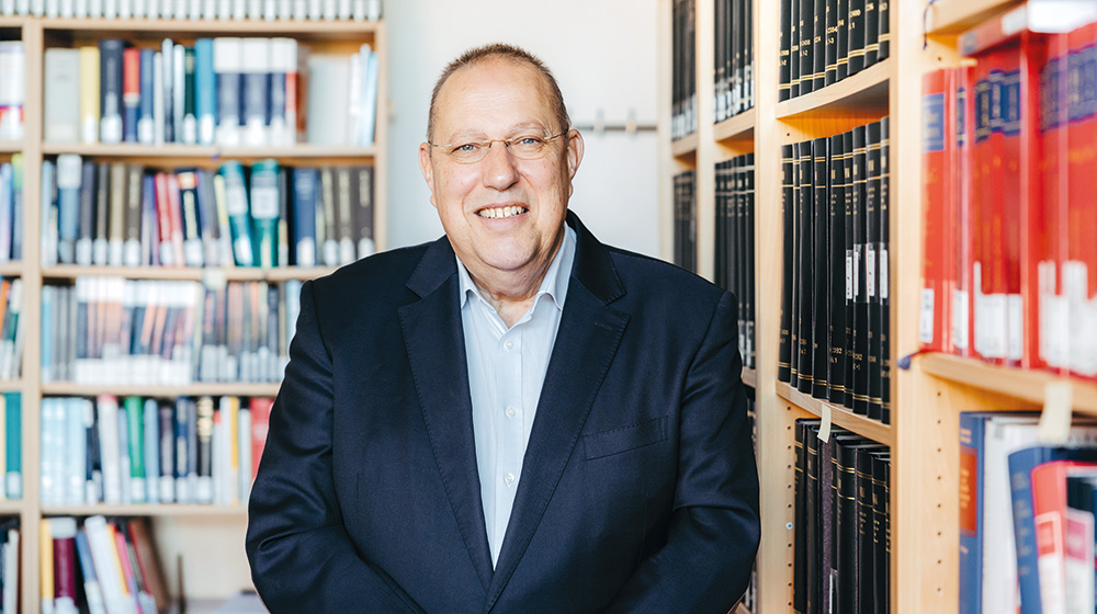Portrait von Prof. Burgard vor zwei Bücherregalen in seinem Büro (Foto: Jana Dünnhaupt / Uni Magdeburg)