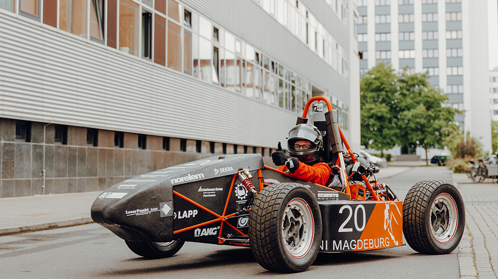 Student sits in the racing car of the UMD Racing Team on the campus of the University of Magdeburg (c) Jana Dünnhaupt Uni Magdeburg