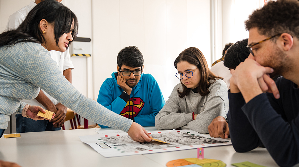 Studierende sitzen bei der Lehrveranstaltung Serious Games an einem Tisch und spielen eines der entwickelten Spiele (c) Jana Dünnhaupt Uni Magdeburg