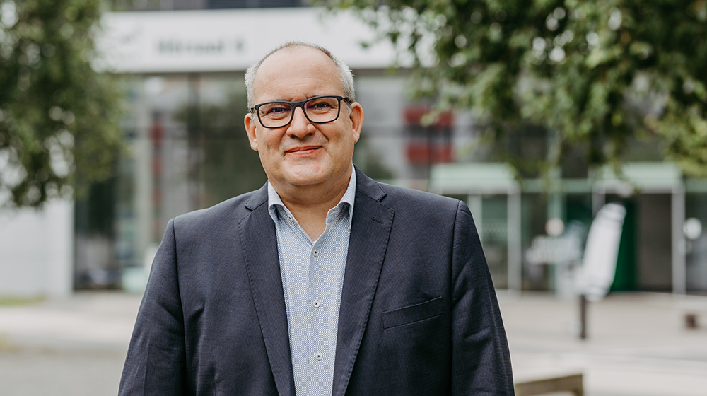 Portrait von Prof. Böcher vor dem Gebäude des Hörsaal 6 der Uni Magdeburg; im Hintergrund sind Bäume zu sehen (c) Jana Dünnhaupt Uni Magdeburg