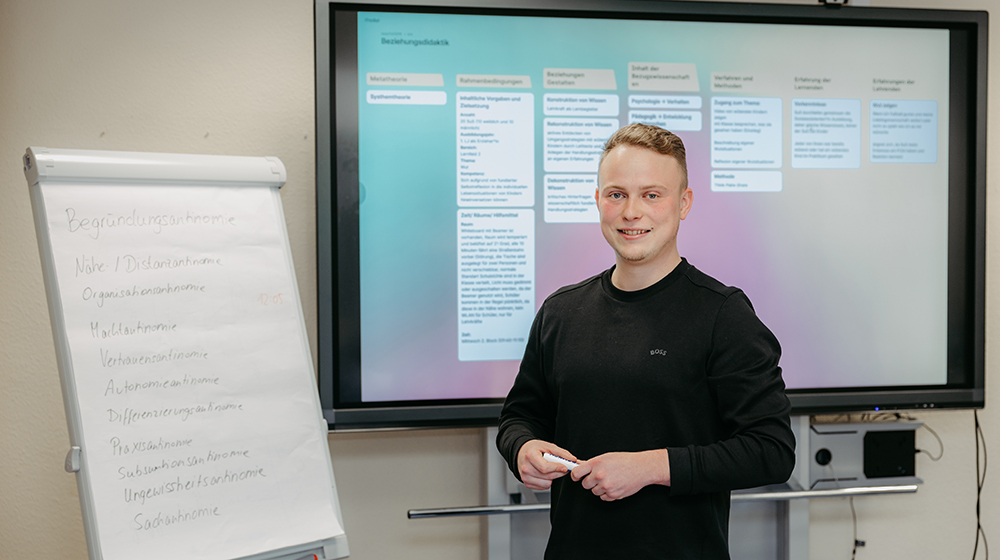 Sascha Muth steht für eine Praxisübung für den Masterstudiengang Lehramt für berufsbildende Schulen in der beruflichen Fachrichtung Sozialpädagogik vor einem Flipchart und großen Bildschirm (c) Jana Dünnhaupt Uni Magdeburg