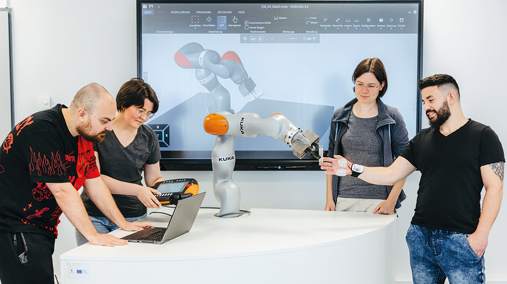 Die Studierenden Vlad Shevtsov, Nadia Schillreff, Anne Rother, Lior Shilon (v. l. n. r.) führen gemeinsam ein Experiment für die Zusammenarbeit von Mensch und Roboter durch (Foto: Jana Dünnhaupt / Uni Magdeburg)