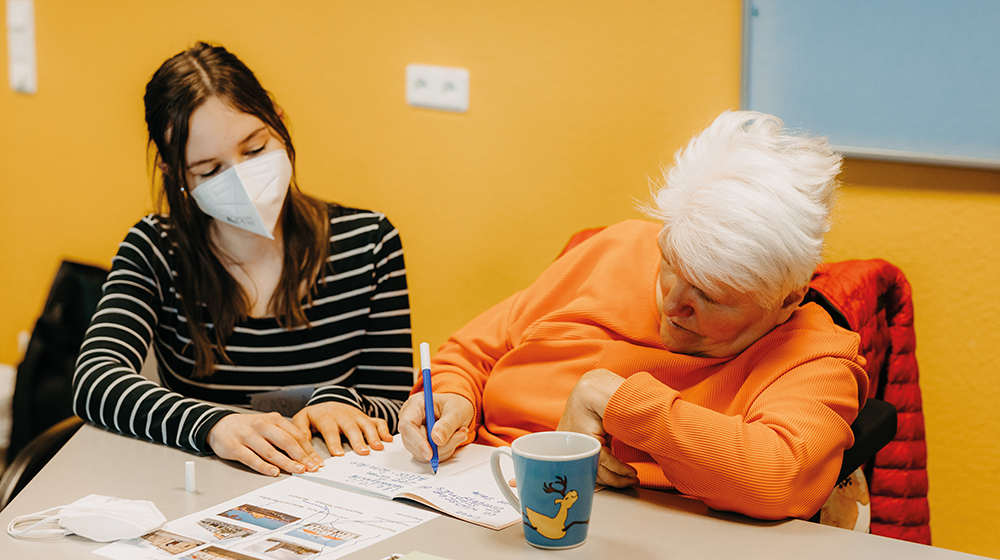 A participant in the inclusive continuing education program doing writing exercises with a student (photo: Jana Duennhaupt / University of Magdeburg)