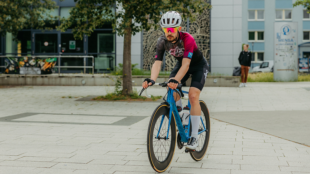 Tim Maihold fährt mit seinem Fahrrad über den Mensavorplatz (Foto: Jana Dünnhaupt / Uni Magdeburg)