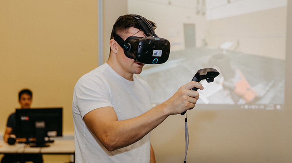 Über die Virtual-Reality-Brille sieht die Testperson eine andere Welt. Mithilfe des Schalters, kann er in der virtuellen Welt Schläger halten oder Bälle werfen.