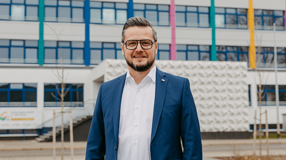 Mike Keune vor seiner Schule - dem  Internationalen Stiftungsgymnasium Magdeburg (Foto: Jana Dünnhaupt / Uni Magdeburg)