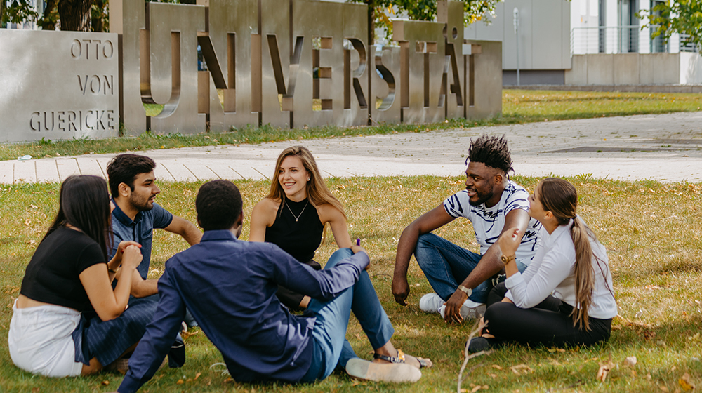 /unimagdeburg_media/Presse/Bilder/Pressemitteilungen/2023/Internationale+Studierende+sitzen+auf+einer+Wiese+vor+der+Uniporta+der+Uni+Magdeburg+%28c%29+Hannah+Theile+Uni+Magdeburg-height-560-width-1000.jpg
