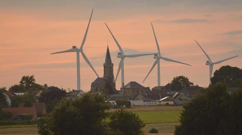 /unimagdeburg_media/Presse/Bilder/Pressemitteilungen/2025/Vier+Windr%C3%A4der+stehen+direkt+am+Rand+einer+Ortschaft+mit+Kirchturm_+Im+Vordergrund+sind+Hecken+zu+sehen_+%28c%29+Doroth%C3%A9e+Quennesson+auf+Pixabay-height-560-width-1000-p-120901.jpg